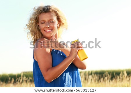 Mature woman applies sun cream outdoor