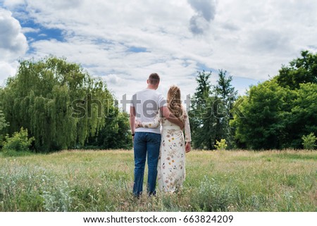 Couple in love embracing and walking outdoors near the forest, back view. Free space