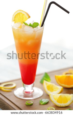 Glass of Tequila Sunrise cocktail on wooden board