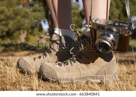 Vintage camera with hiking boots on the ground. Travel background