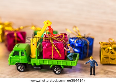 Miniature Worker Passenger Gift Box by Truck on Wooden floor ,Image for Christmas Holiday and Happy New Year Gift Celebration concept.