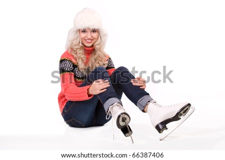 Pretty blond girl sitting with figure skates on white background