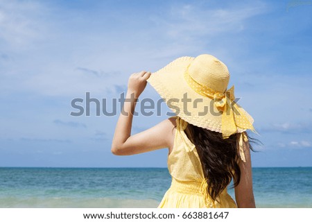 Happy woman enjoying beach relaxing joyful in summer by tropical blue water. Beautiful dress model happy on travel wearing beach sun hat on beach.