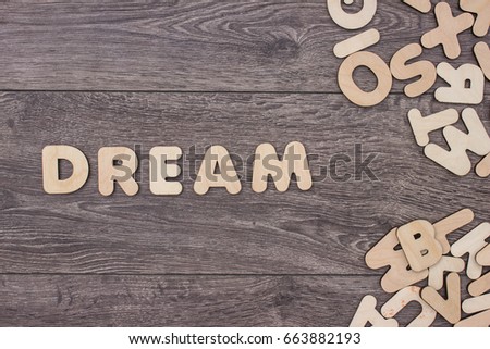 Word Dream made with wooden letters next to a pile of other letters over the wooden board surface composition