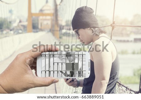 Man hand holding horizontal the white smart phone prison bar and Asian man use phone on the bridge,Danger of social