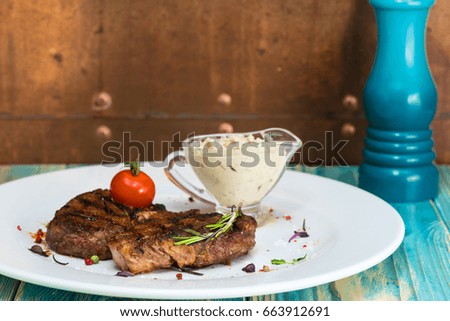 delicious steak from marble beef medium rare with tomatoes and herbs on a white plate, on a  wooden table. Brown background with copy space for text