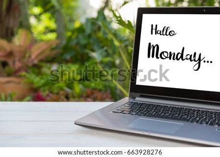 Monday text wrote on screen laptop over wood table with green garden background
