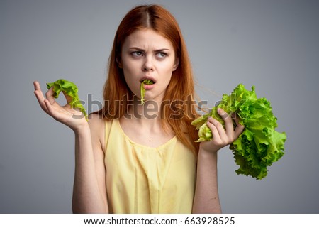 Diet, healthy food, lettuce, woman eats lettuce, woman on gray background                               