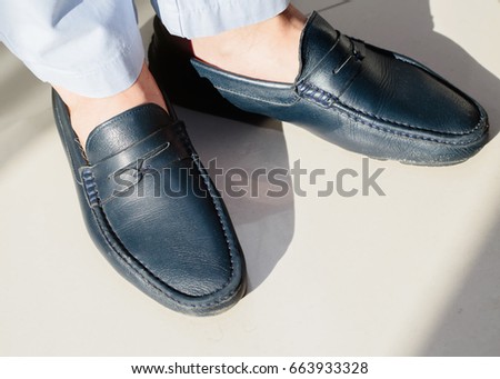 Pair male classic shoes on white .closeup.Man wearing short grey pants and dark blue italian shoes without socks