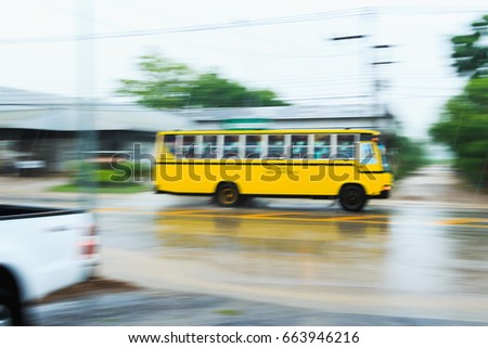 blurred school bus  running on the road in raining day.