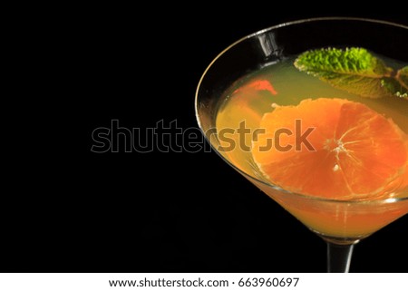 Orange jelly with orange piece in the glass topped mint leaves on the black background