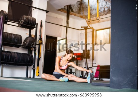 Attractive girl is stretching up with smile, in cross fit gym