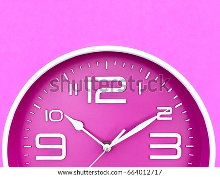 Closeup A half of deep pink wall clock set on pink background. Top view with copy space. Selective focus.