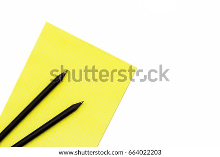Two black pencil and a yellow Notepad on a white background. Flat lay minimal concept workplace at the office. Top view.
