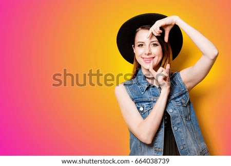 Young woman holding imagination camera on yellow background