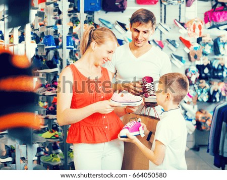  positive  family of three choosing pair of sneackers in shoes store
