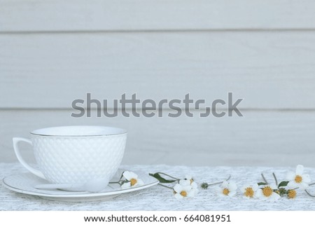 Coffee cup with chamomile flower on white lace,vintage background