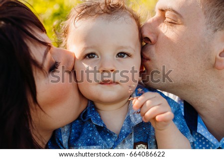 Parents kiss pretty little boy