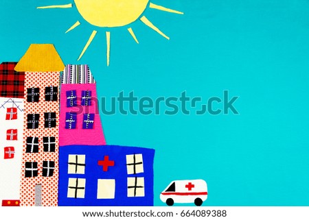 Fabric town. Houses, the sun and ambulance made of colorful pieces of fabric isolated on blue background. 