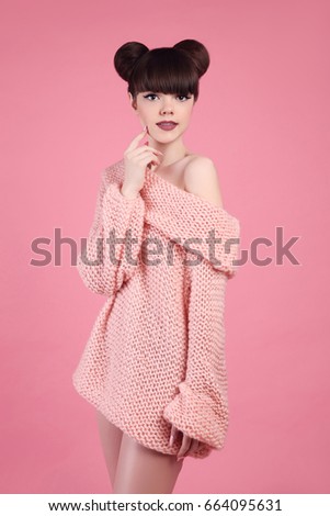 Beauty makeup. Fashion teen girl model. Brunette with matte lips and hairstyle wearing wool sweater posing over studio pink background.