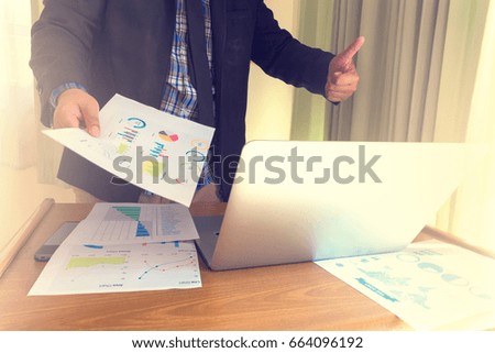 Business man working and thump up at office with laptop and documents on his desk, vintage photo
