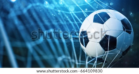 Soccer ball in goal on blue background Royalty-Free Stock Photo #664109830