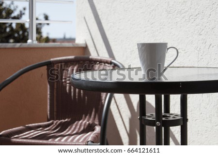 Cup of coffee on the balcony with the shadows from the sun, geometric composition
