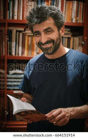 Curious man choosing book in his library at home. Close up