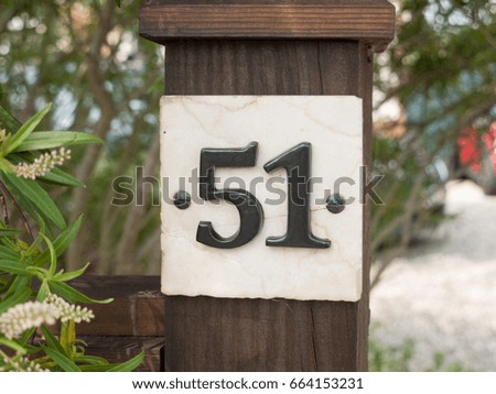 white house number plate 51 on post outside in garden