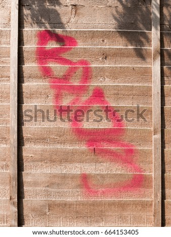 a red spray paint stain outside on a wooden garden fence