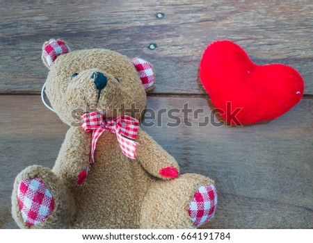 Bear doll with red heart on wooden background