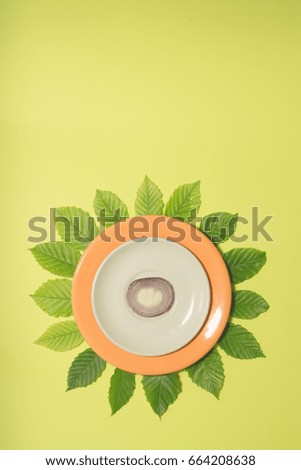 Onion slice on white and orange plate over leaves and lime green colored background. Vertical design for a leaflet, banner, cover or flyer