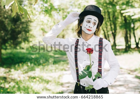 Emotional male mime artist with red rose performing love on a outdoor.