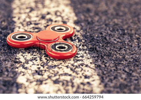 Popular spinner gadget in 2017 on a blue and white background. Modern red plastic spinner fidget game for young people.