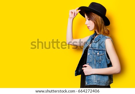 Portrait of young adult woman in hat on yellow background