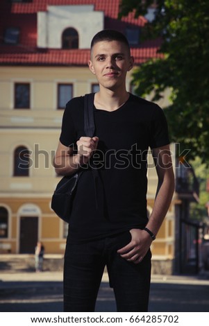 happiness and people concept - smiling man in black t-shirt over house background, toned photo