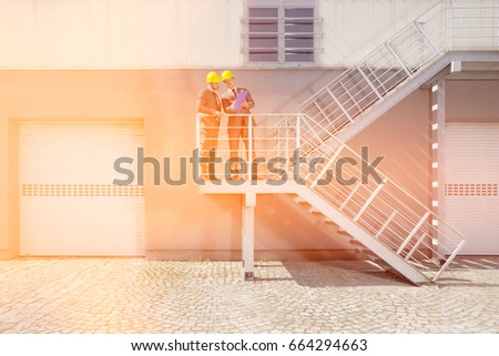Young male engineers with clipboard discussing on stairway