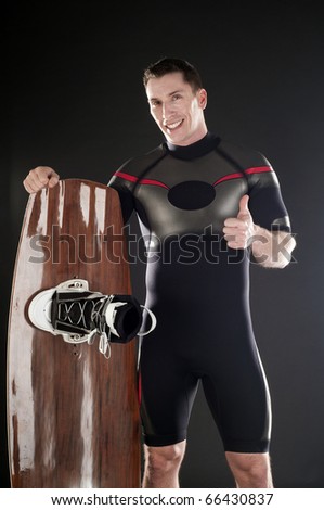 Man in wetsuit and wake board on black background