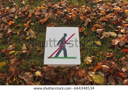 Interesting sign seen in Paris - Man walking with red line meaning DO NOT WALK in this area - fall colored leaves in background
