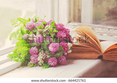 Bouquet of clover and old book on the windowsill. 