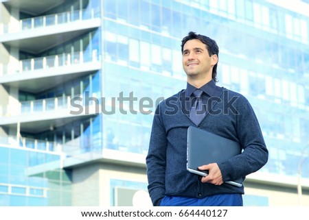 Portrait of a business man with a laptop in hand on the background of an office building.