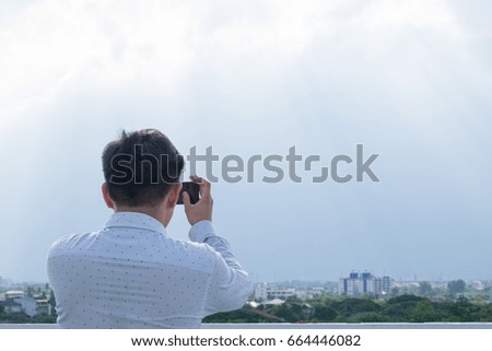 Man taking a photo of cityscape view with smartphone.