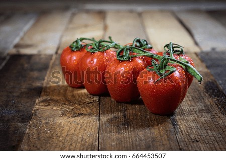 Rosa on tasty Italian tomatoes, wooden table, black background