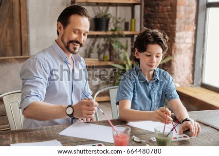 Happy father and his son focused on painting