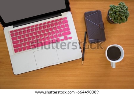Wooden designer desktop with sleep screen laptop, stationery items, coffee cup, cell phone, calculator and pencil, selective focus