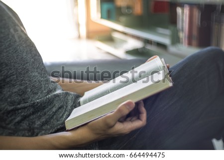 Young man reading old book in public library. blur background