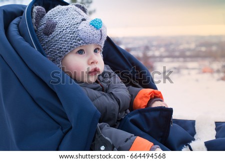 Portrait of a cute boy on a sled during a family walk in winter. Outdoor fun for family Christmas vacation. Little boy sitting in a sleigh. Copy space. Space for text. Sunset.
