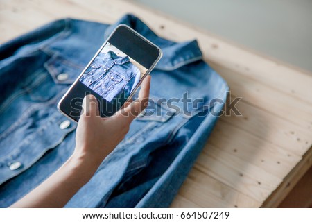 young Women taking photo to shirts with cell telephone or smartphone digital camera for Post to sell Online on the Internet . Royalty-Free Stock Photo #664507249