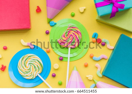 Birthday concept with wrapped gifts, greeting cards and sweets on yellow background top view