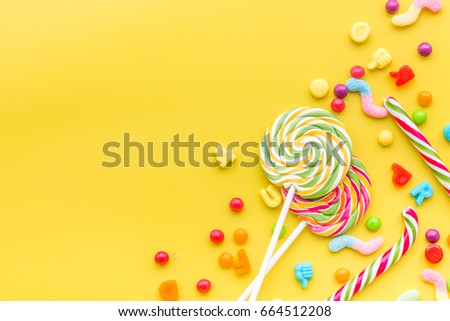 Sweets for birthday including lollipop and drops on yellow background top view copyspace